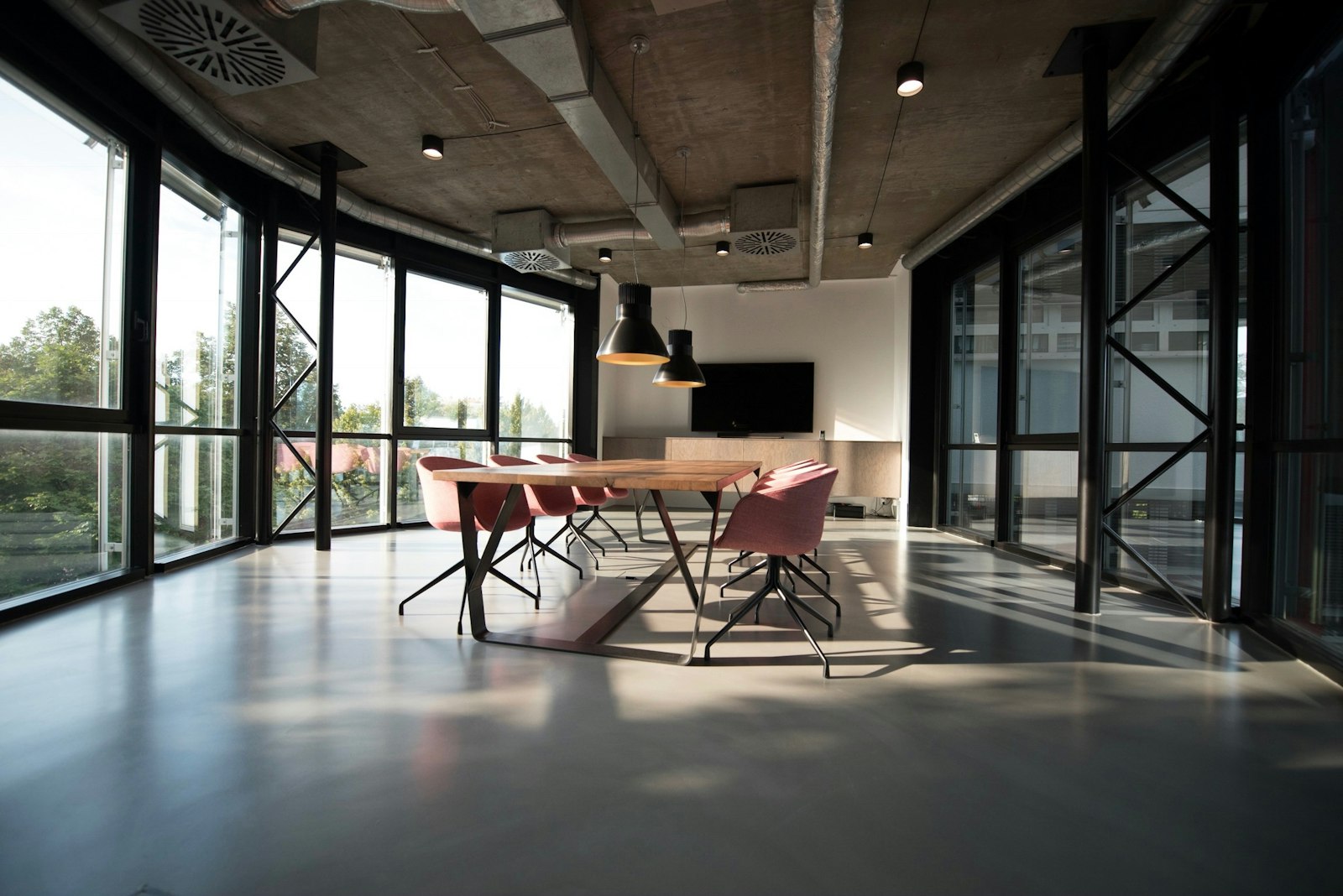 A meeting room with a long timber table and glass partitions.